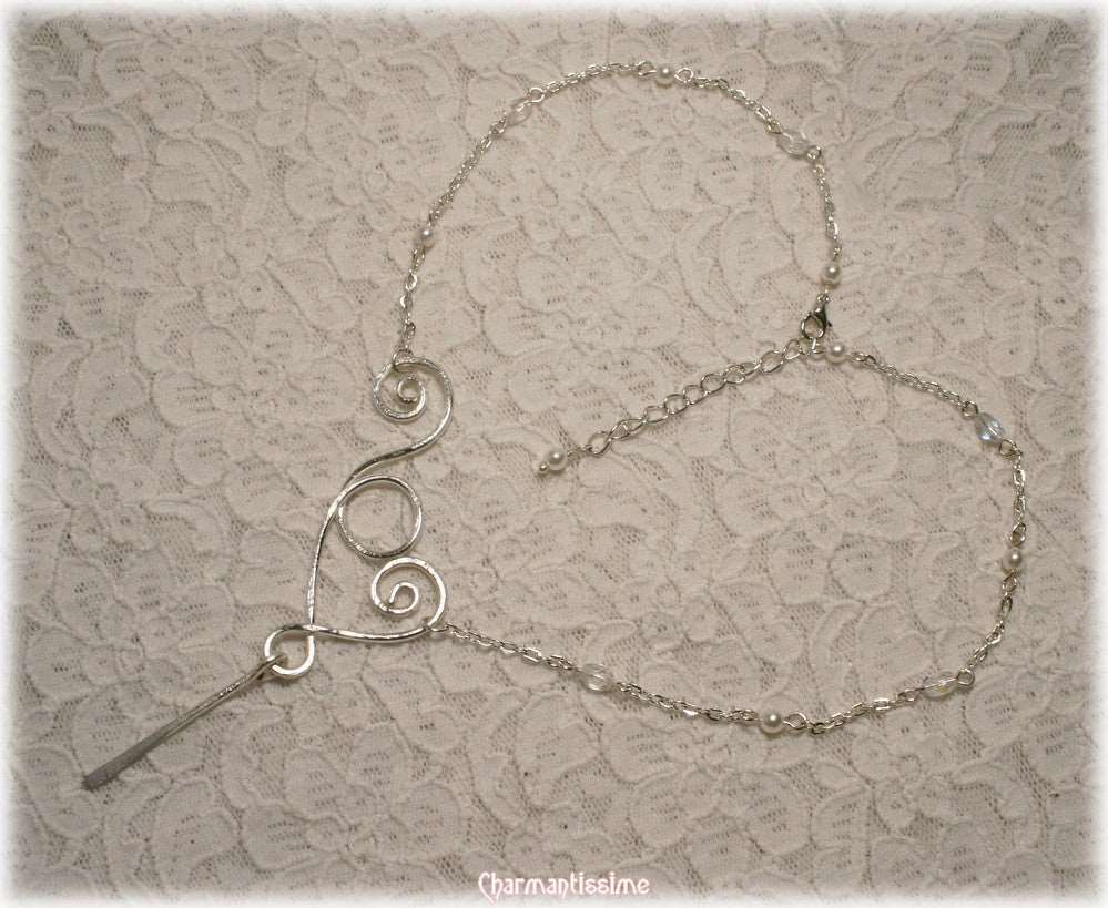 Magnifique collier minimaliste de créateur en volutes de métal argenté, d'inspiration atlante et revisité art contemporain formant un joli coeur asymétrique stylisé.